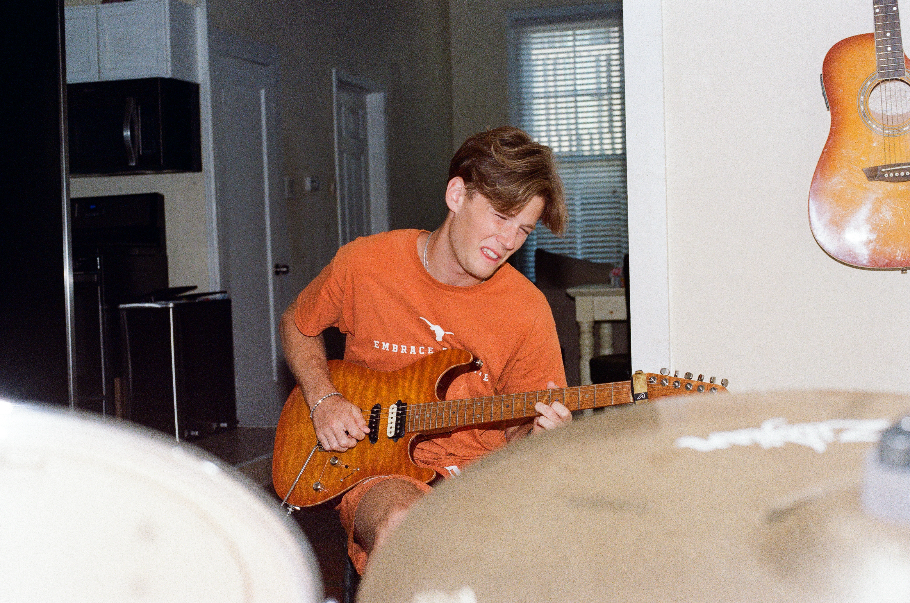 Evan MacGregor playing guitar at home in UT Longhorns shirt