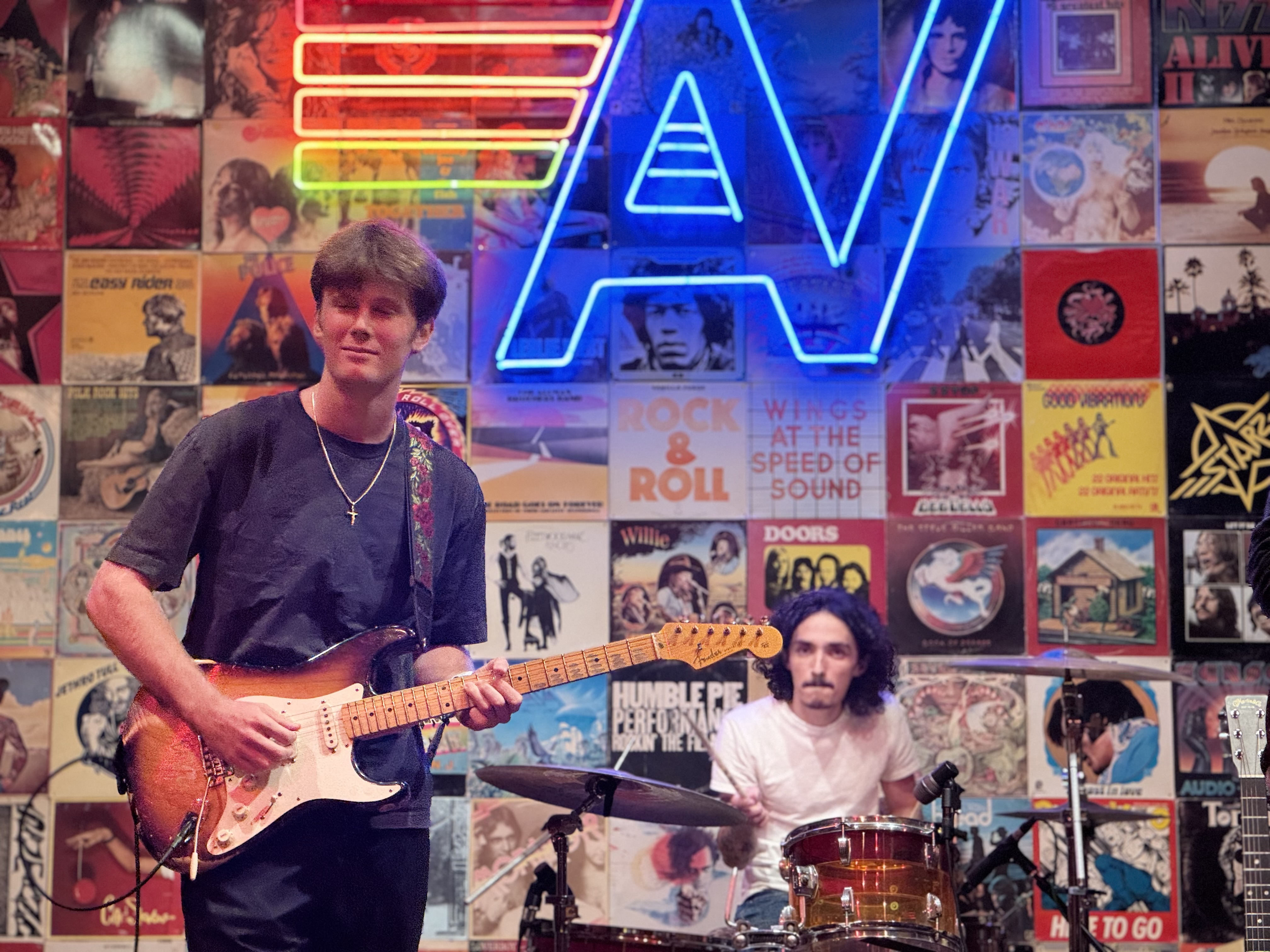 Evan MacGregor performing live with band in front of vinyl record wall